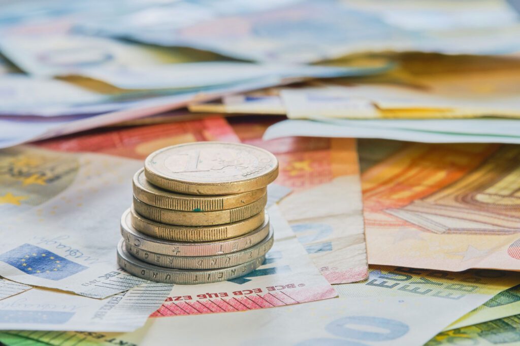 Gestapelte Euromünzen auf mehreren Euro-Geldscheinen als Symbol für Finanzen und Haushalt.