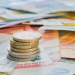 Gestapelte Euromünzen auf mehreren Euro-Geldscheinen als Symbol für Finanzen und Haushalt.
